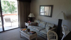 A living room with a sofa, two chairs, a coffee table, and a window with curtains.