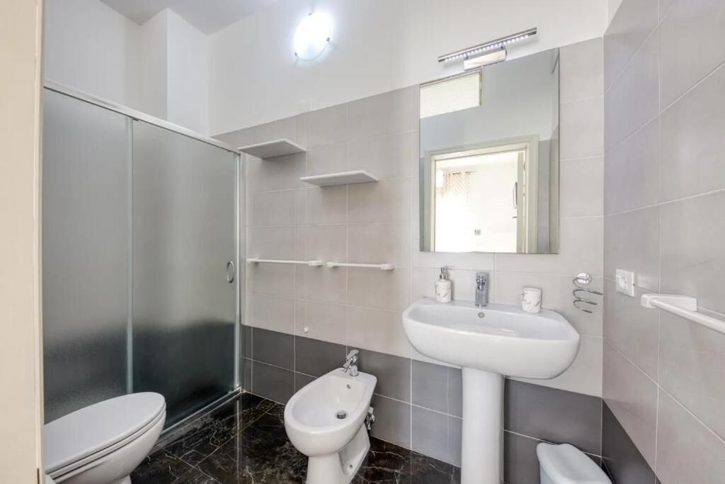 A modern bathroom with a toilet, bidet, and a glass shower enclosure.