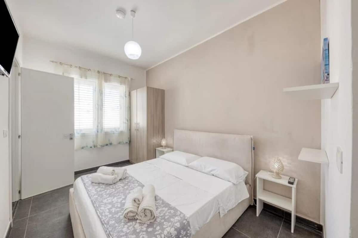 A bedroom with a bed, bedside tables, a nightstand, and a lamp.
