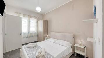 Quarto com cama, mesas de cabeceira e abajur.