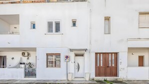 A white two-story residential building with a central door, small windows, and a balcony. - Il Comandante (Torre San Giovanni)