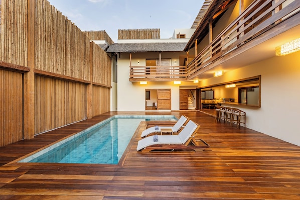 A pool area with wooden flooring, two lounge chairs, and a wooden fence. - Villa Shamsa - Suítes Deluxe 2  (Jijoca de Jericoacoara)