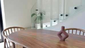 Ett modernt matområde med ett träbord och stolar, ett glasräcke och en trappa i bakgrunden.