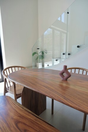 A modern dining area with a wooden table and chairs, a glass railing, and a staircase in the background. - 2-bedroom Oceanview Loft N°7: Mare (La Libertad)