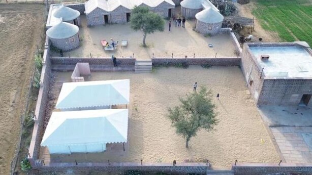 A fenced compound with multiple buildings, including a large tent-like structure and several dome-shaped buildings. - Double room 5 at Osian Dhani Rajasthan (Khetasar)