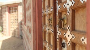 A wooden door with decorative metal cutouts and a brass handle.