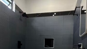 A modern bathroom with a white toilet, a shower area, and a sink with a mirror. - Storebay Suites - Apartment 5- (Tobago)