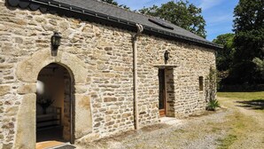 Ein Steinhaus mit zwei Rundbogenportalen und einem kleinen Eingang.