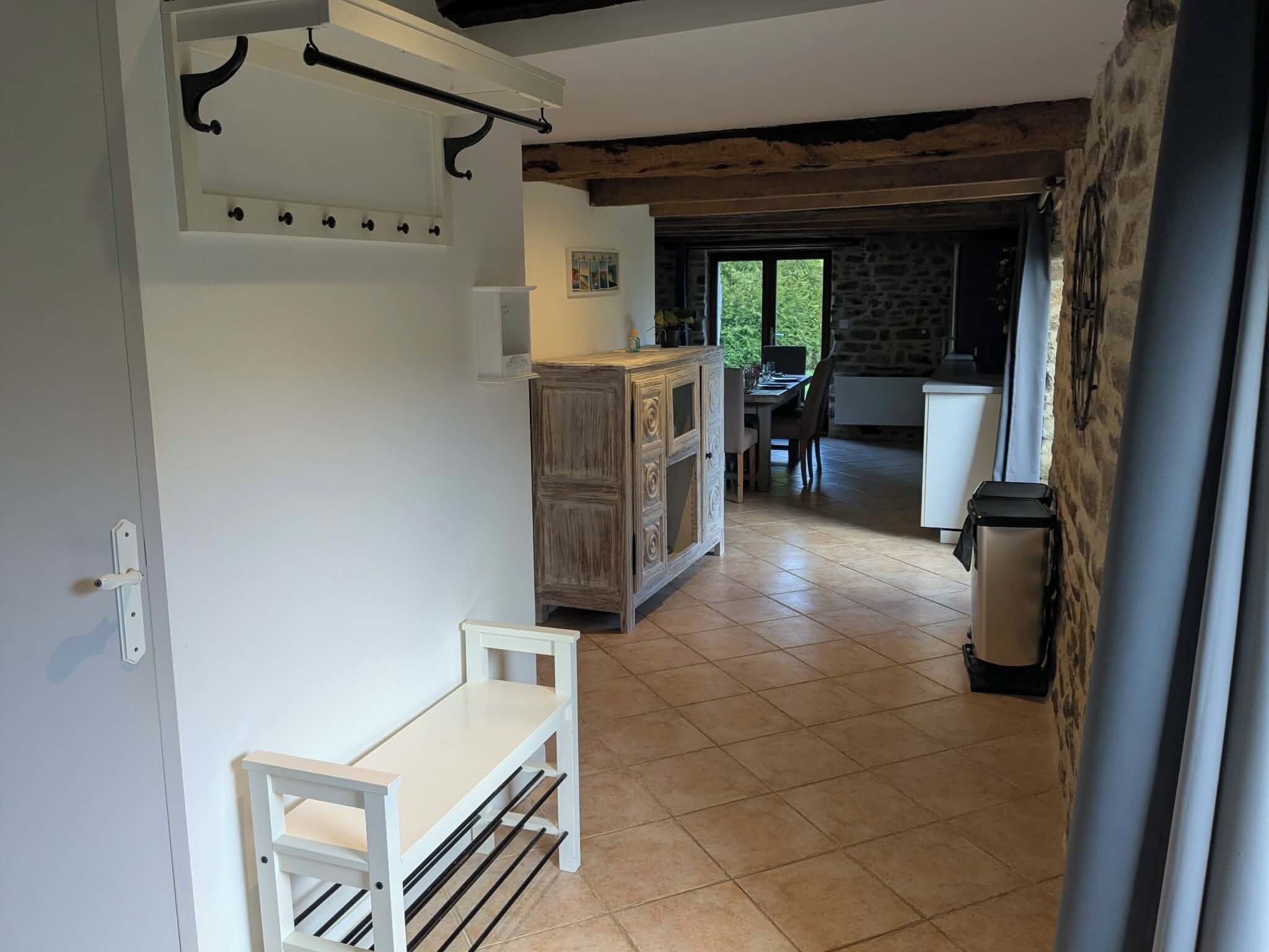Un'ampia cucina con zona pranzo, una panca bianca e una parete in pietra.