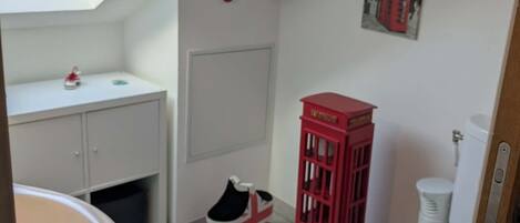 A compact bathroom with a skylight, a red telephone booth, and a Union Jack bag.