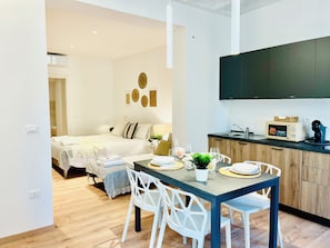 Eine moderne Wohnung mit Essbereich, einer Küche inklusive Mikrowelle und einem Bett mit Blick.