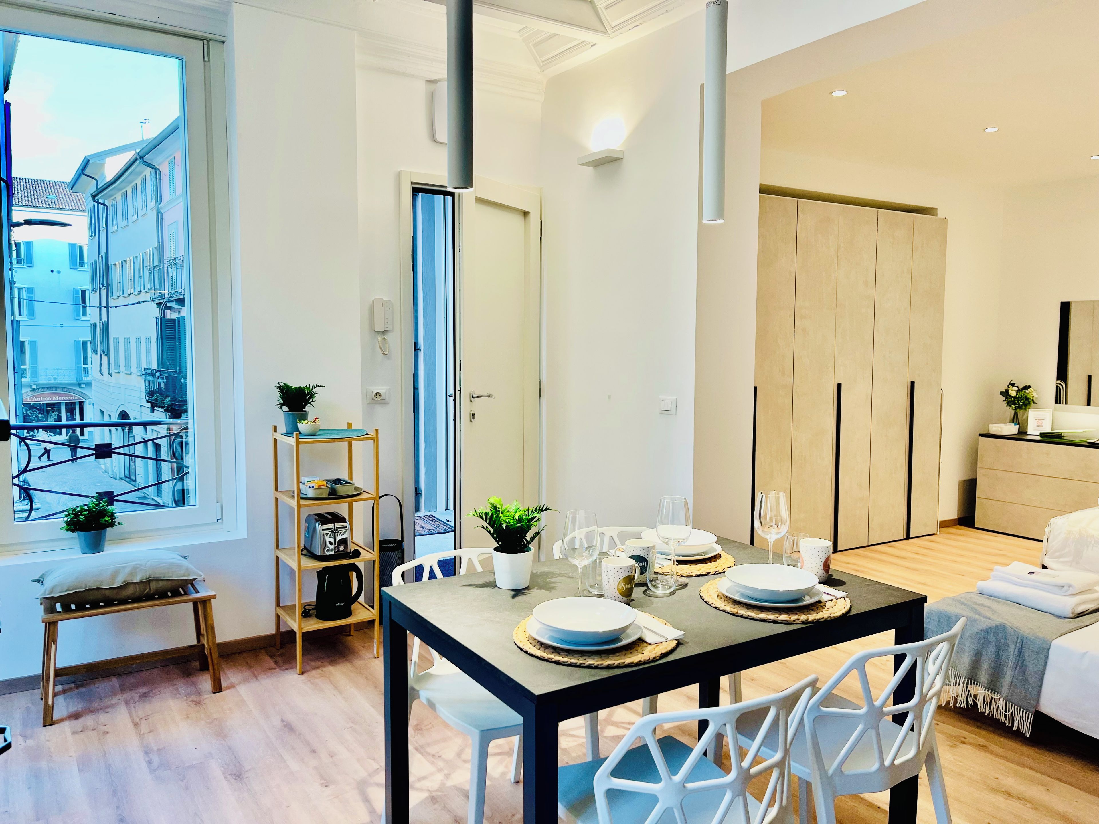A modern hotel room with a dining area, a bed, and a view of the street.