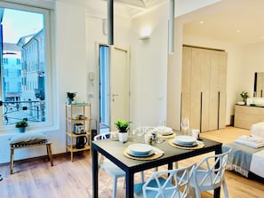 Une chambre d’hôtel moderne avec un coin repas, un lit et vue sur la rue.