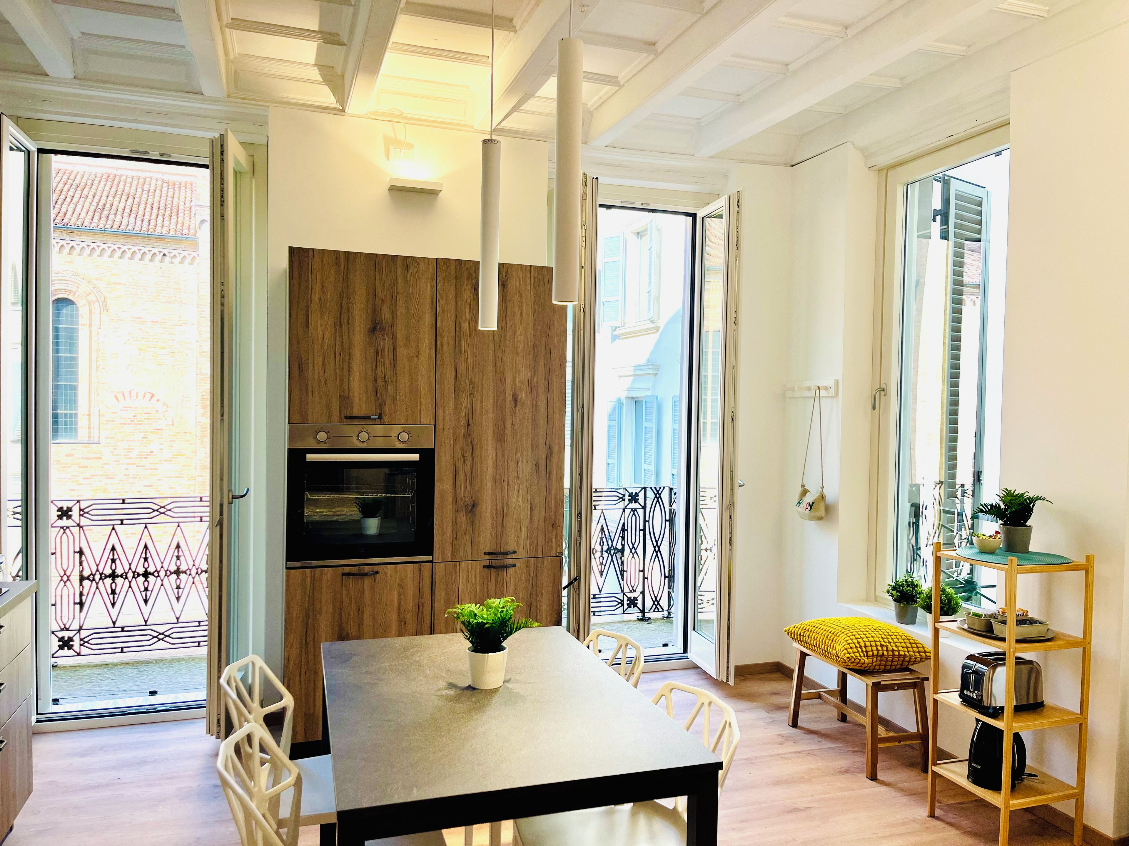 A modern kitchen with wooden cabinets, a built-in oven, and a dining area with a table and chairs.