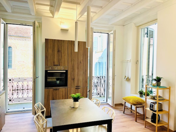 Une cuisine moderne avec des meubles en bois, un four encastré et un coin repas comprenant une table et des chaises.