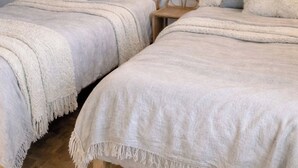 Una camera da letto con due letti, un lampadario a parete e una piccola sedia di legno.