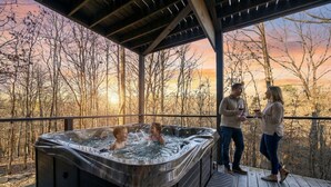 A hot tub on a wooden deck with a view of trees and a sunset. - New! Private Heated Pool, Hot Tub, Game Room, Fire Pit & Bunk Room - Near Trails (Broken Bow)