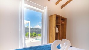 Ein Schlafzimmer mit Bett, einem Holzschrank und Blick auf einen Pool.
