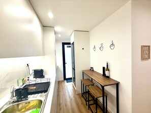A narrow kitchen with a wooden countertop, a sink, and a black chair. A bottle of wine is on the countertop. - Cc House Gaia (Vila Nova de Gaia)
