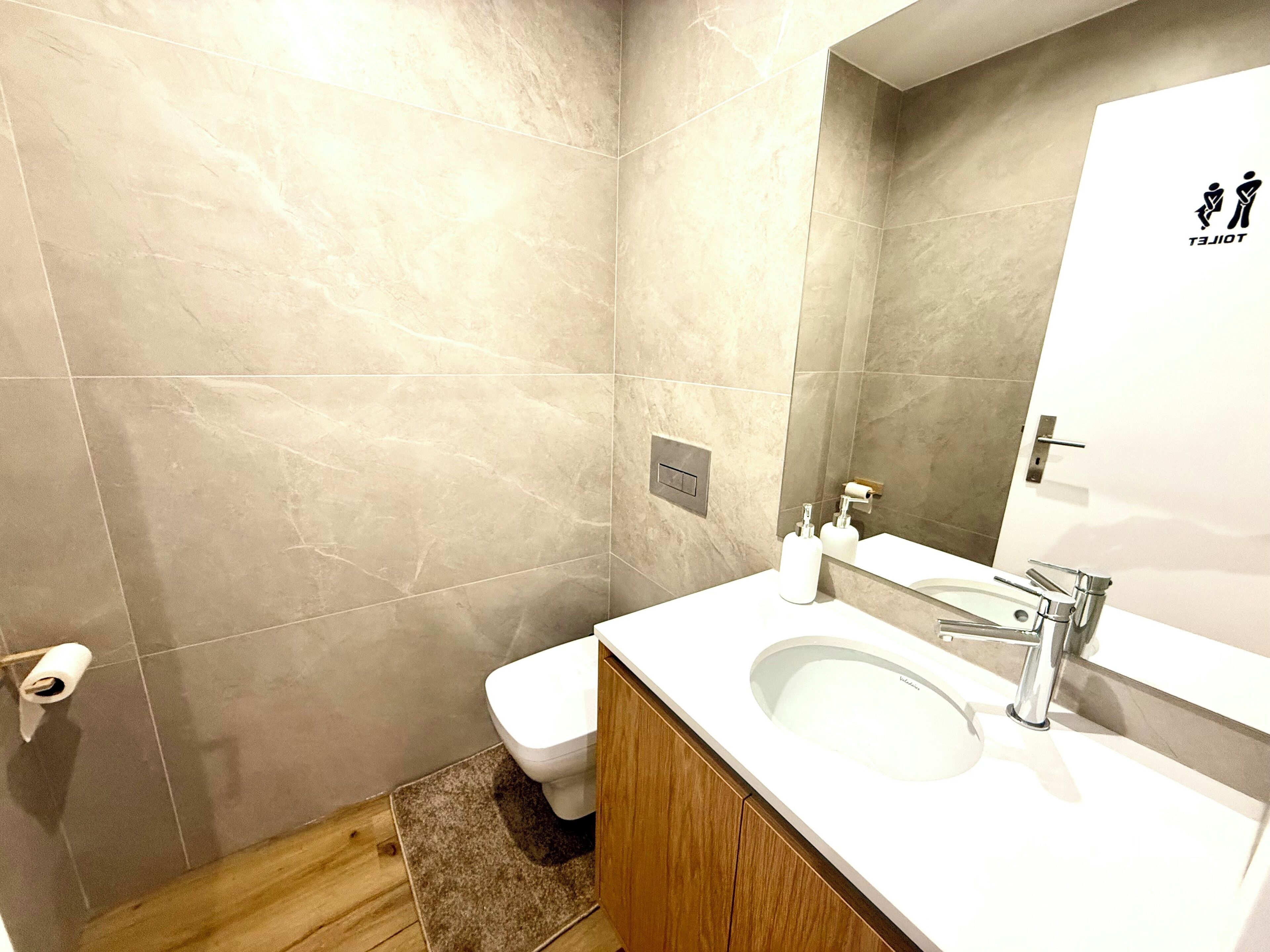 Ein modernes Badezimmer mit Toilette, Waschbecken und Spiegel.