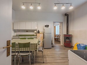 A compact kitchen with a dining area, a microwave, a refrigerator, and a wood-burning stove. - Catherine by Interhome (Pellizzano)