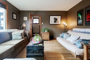 A cozy living room with a sofa, a wooden coffee table with a plant, and a vintage trunk.