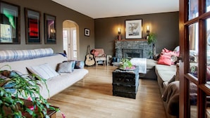 Een gezellige woonkamer met een stenen openhaard, een bank, een salontafel en een gitaar.