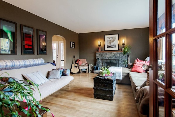 A cozy living room with a stone fireplace, a sofa, a coffee table, and a guitar.