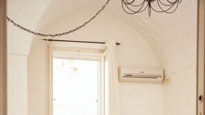 En matplats med ett vitt bord dukat för fyra personer, en korg av rotting och en vit vas med blommor.