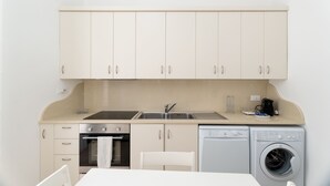 A compact kitchenette with a stove, oven, sink, and a washing machine. - Casa Argento by Monholiday (Monopoli)