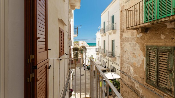 A narrow street with buildings on either side, balconies, and a clear blue sky. - Casa Argento by Monholiday (Monopoli)