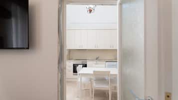 A kitchen with white cabinets, a dining table with chairs, and a TV mounted on the wall.