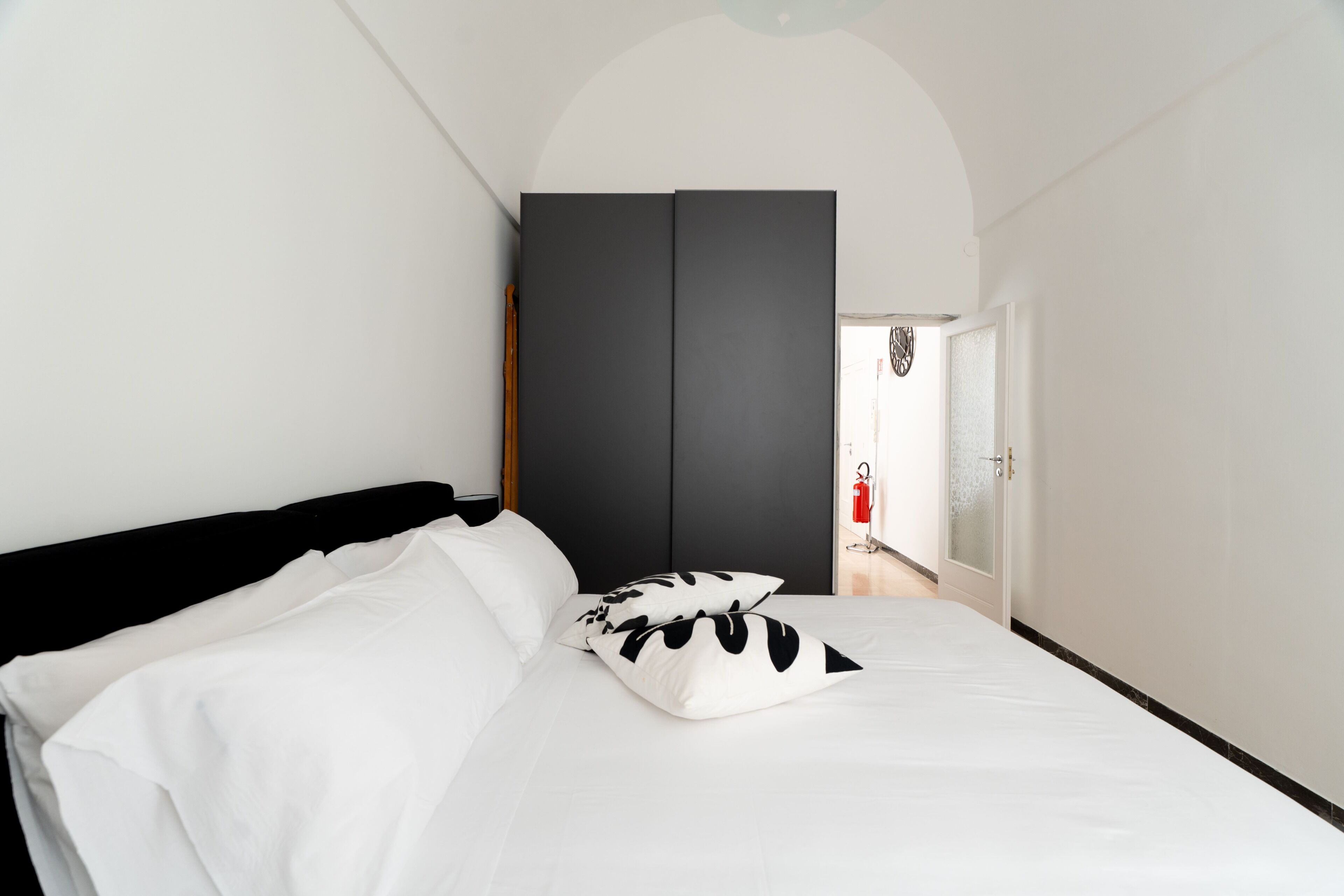 Une chambre à coucher comprenant un lit, une armoire et une porte donnant sur un couloir.