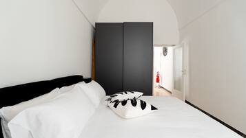 Une chambre à coucher comprenant un lit, une armoire et une porte donnant sur un couloir.