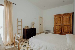 Une chambre à coucher avec un lit, une armoire en bois, un bureau avec une lampe, une chaise et une échelle.