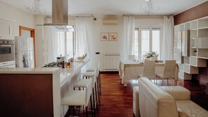 Una cocina moderna con comedor, muebles blancos y una estantería empotrada.