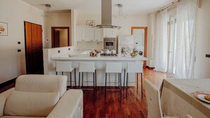 Una cocina moderna con armarios blancos, una isla central con taburetes y una zona de comedor con mesa y sillas.