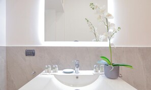 A bathroom with a white sink, a mirror, a potted orchid, and a small window. - Flatsharing - Scarlatti - 2 camere (Milan)