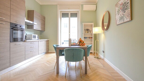A modern kitchen with built-in appliances, a dining area with a table and chairs, and a view of the outside through a door. - Flatsharing - Scarlatti - 2 camere (Milan)