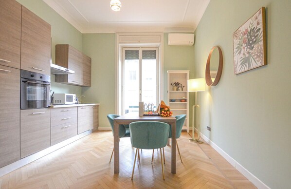A modern kitchen with built-in appliances, a dining area with a table and chairs, and a view of the outside through a door. - Flatsharing - Scarlatti - 2 camere (Milan)