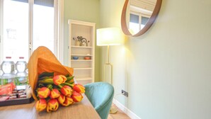 A room with a wooden table, a bouquet of tulips, a teal chair, a white shelf with kitchen items, and a floor lamp. - Flatsharing - Scarlatti - 2 camere (Milan)