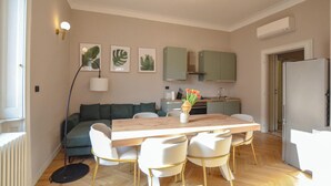 A modern living space with a dining area, sofa, kitchen, and a radiator. - Flatsharing - Scarlatti - 3 camere (Milan)