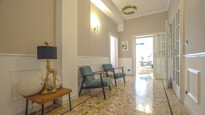 A hallway with a patterned floor, a lamp, two chairs, and a door leading to another room. - Flatsharing - Scarlatti - 3 camere (Milan)