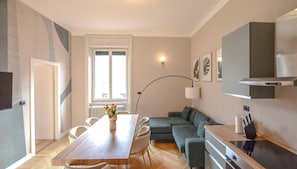 Ein modernes Wohnzimmer mit Esstisch, Sofa und Küchenzeile.