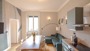 Ein modernes Wohnzimmer mit Esstisch, Sofa und Küchenzeile.