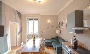 Ein modernes Wohnzimmer mit Esstisch, Sofa und Küchenzeile.