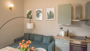 Ein Hotelzimmer mit einem Bett, einem Schreibtisch, einer Lampe, einem Strauß Tulpen und gerahmten Pflanzenbildern an der Wand.