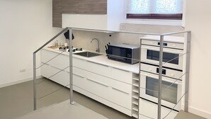 Ett modernt kök med vita skåp, en rostfri köksfläkt och en inbyggd ugn.