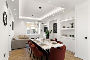 A modern dining area with a long table, red chairs, and white walls. - Apartment - Sleeps 8 - Golders Green 10 mins (London)