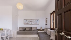 Een moderne kamer met een bed, een eettafel en stoelen. Er hangt een schilderij aan de muur en op een bijzettafeltje staat een decoratieve vaas.